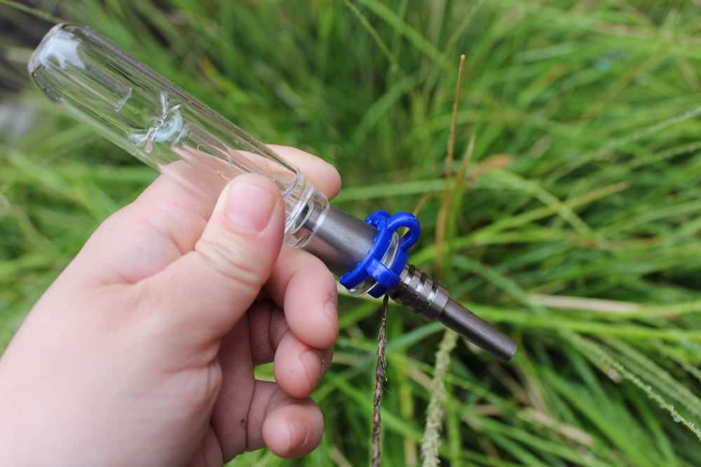 a hand holding a glass tube with a blue ring around it